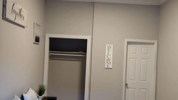 A bedroom with a bed, a closet, a door, and a wall-mounted sign. - lovely relaxing room with hight speed internet , neflix with a independent entry (Goose Creek)
