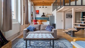 Amplia sala de estar con sofá, una mesa de centro y una escalera que conduce a un nivel superior.