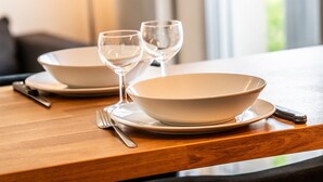 Una mesa de comedor con dos cuencos, dos copas de vino, un tenedor y un cuchillo.