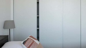 A hotel room with a bed, a nightstand with a lamp, and a sliding door closet.