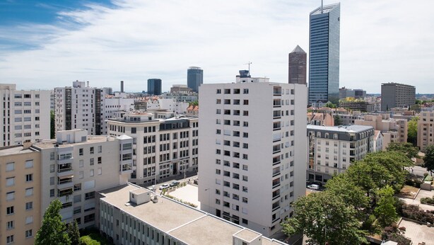 A cityscape with modern high-rise buildings, including a prominent skyscraper.