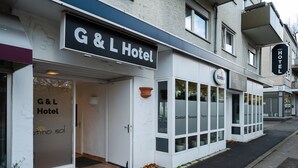 The exterior of G&L Hotel with a clear entrance, a visible sign, and a potted plant near the entrance. - G & L Hotel (Dortmund)