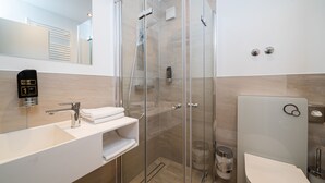 A modern bathroom with a glass-enclosed shower, a white sink with a towel rack, and a toilet. - G & L Hotel (Dortmund)