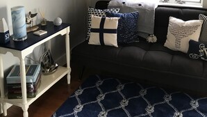 Un salon avec un canapé foncé, un tapis à motifs, un miroir décoratif et des tableaux encadrés accrochés au mur.