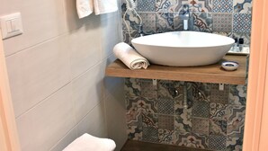 Un baño con un lavamanos grande, un perchero y un taburete de madera.