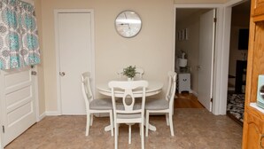 A dining area with a round table and four chairs, a clock on the wall, and a patterned curtain. - Large 4 Bedroom CT Home Comfy for Longer Stay (Bristol)