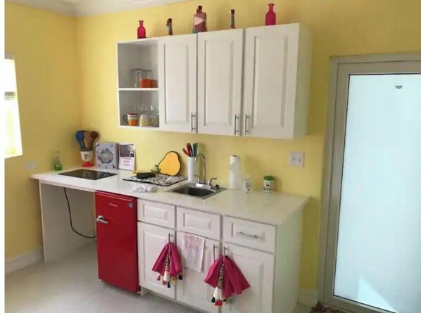 A compact kitchen with white cabinets, a red dishwasher, and a yellow wall.