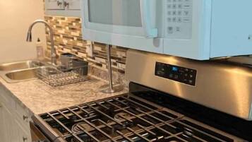 A kitchen with white cabinets, a stainless steel stove, and a microwave.