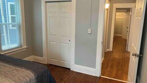 Ein Schlafzimmer mit Bett, Schrank und einem zur anderen Kammer führenden Flur.