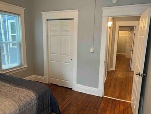 Ein Schlafzimmer mit Bett, Schrank und einem zur anderen Kammer führenden Flur.