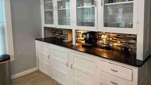 Una cocina con armarios blancos, encimera negra y una cafetera.