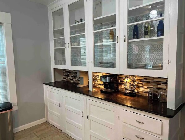 A kitchen with white cabinets, a black countertop, and a coffee machine. - Beautiful furnished 2 bdr great location Elmwood (Buffalo)