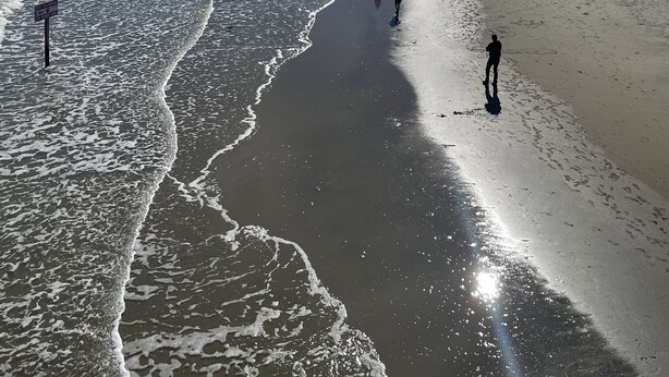 Une plage avec des vagues, des gens et des bâtiments en arrière-plan.