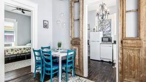 Un coin repas avec une table et des chaises, une cuisine en arrière-plan et une porte en bois.