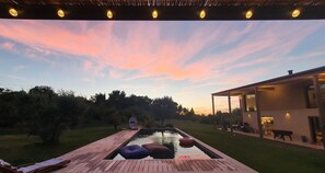 Relax by the pool on a spacious deck surrounded by lush greenery and trees.