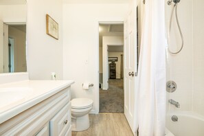 Une salle de bain avec un meuble-lavabo blanc, des toilettes et un espace douche.