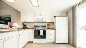 Cocina moderna con armarios blancos, estufa, microondas y refrigerador.