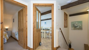 Ein Korridor mit Holztüren, der in einen Essbereich mit Tisch und Stühlen führt.