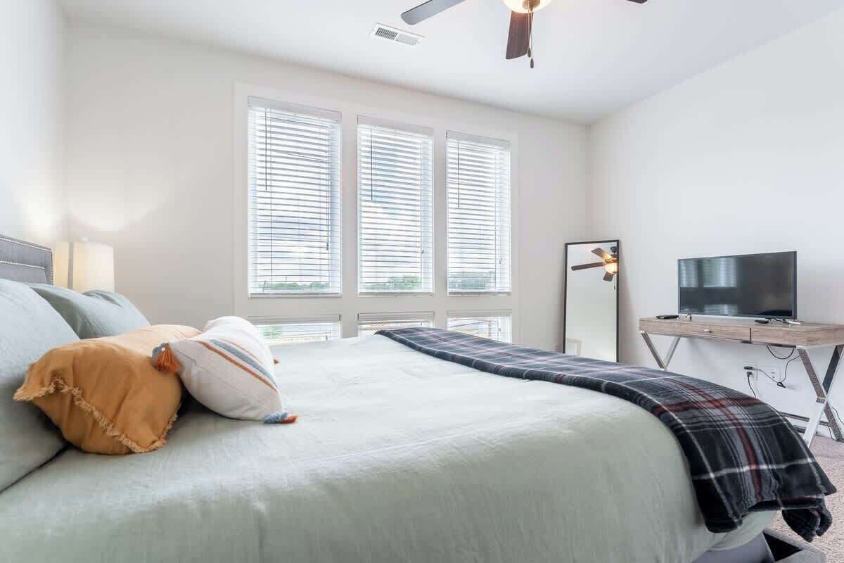 Une chambre à coucher avec un lit, une télévision et une fenêtre équipée de stores.