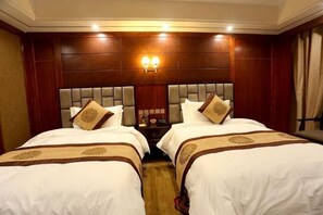 A hotel room with two beds, a wooden headboard, and a nightstand with a lamp. - Banak Shol Hotel (Lhasa)