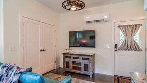 A living room with a blue sofa, a wooden cabinet, a flat-screen TV, and a ceiling light fixture. - Rustic Studio Walkable to Music Row (Nashville)