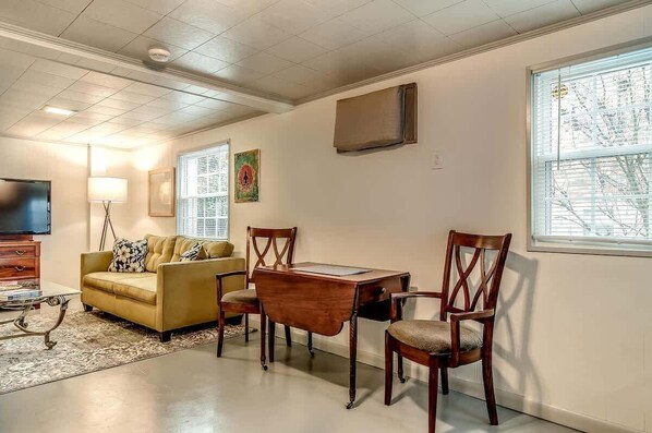 Una sala de estar con sofá, mesa de centro, televisor y un comedor con sillas y una mesa.