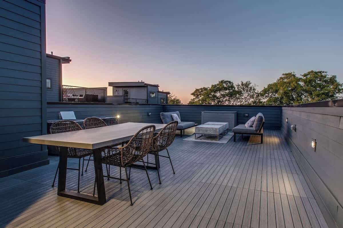 A rooftop deck with a dining table and chairs, a sofa, and a small table.