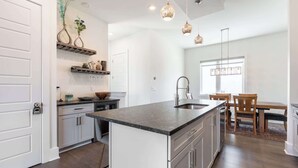 A modern kitchen with a central island, white cabinetry, and pendant lighting.