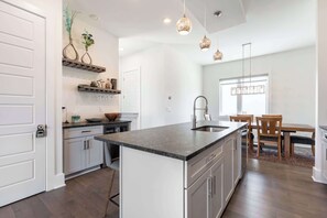 A modern kitchen with a central island, white cabinetry, and pendant lighting. - The East Side Vibe - Spacious Home in Great (Nashville)
