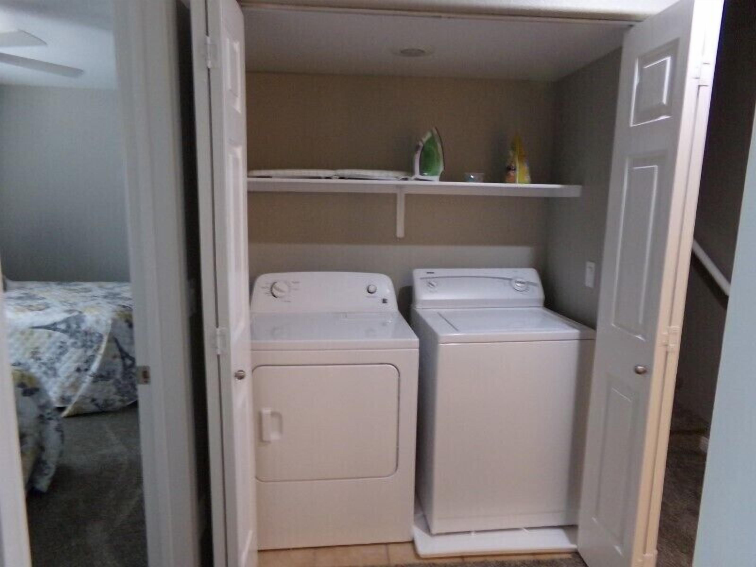 Un cuarto de lavado con dos lavadoras blancas y un estante arriba.