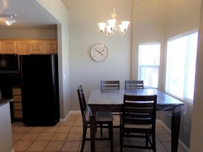 A kitchen with wooden cabinets, a black refrigerator, a dining table with four chairs, a wall clock, and a chandelier. - The Shooting Star by Mesquite Vacation Rentals with Community Pool and $510 in free daily activities (Mesquite)