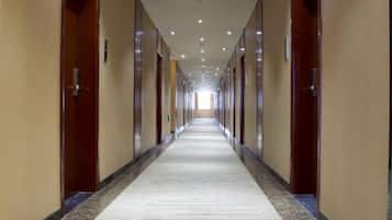 A long, narrow hotel corridor with doors on both sides, leading to individual rooms.
