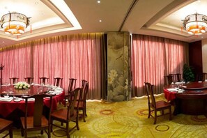 A hotel dining area with round tables, chairs, and curtains. - Jiangbin Hotel (Fusui)