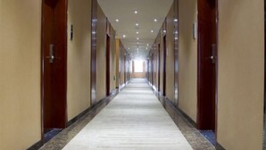 Um corredor de hotel comprido e estreito, com portas de ambos os lados, que dá acesso aos quartos.
