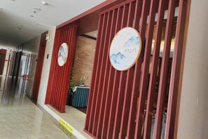 A hotel reception area with a modern design, featuring a reception desk and a waiting area with a view of the hallway. - Jiangbin Hotel (Fusui)