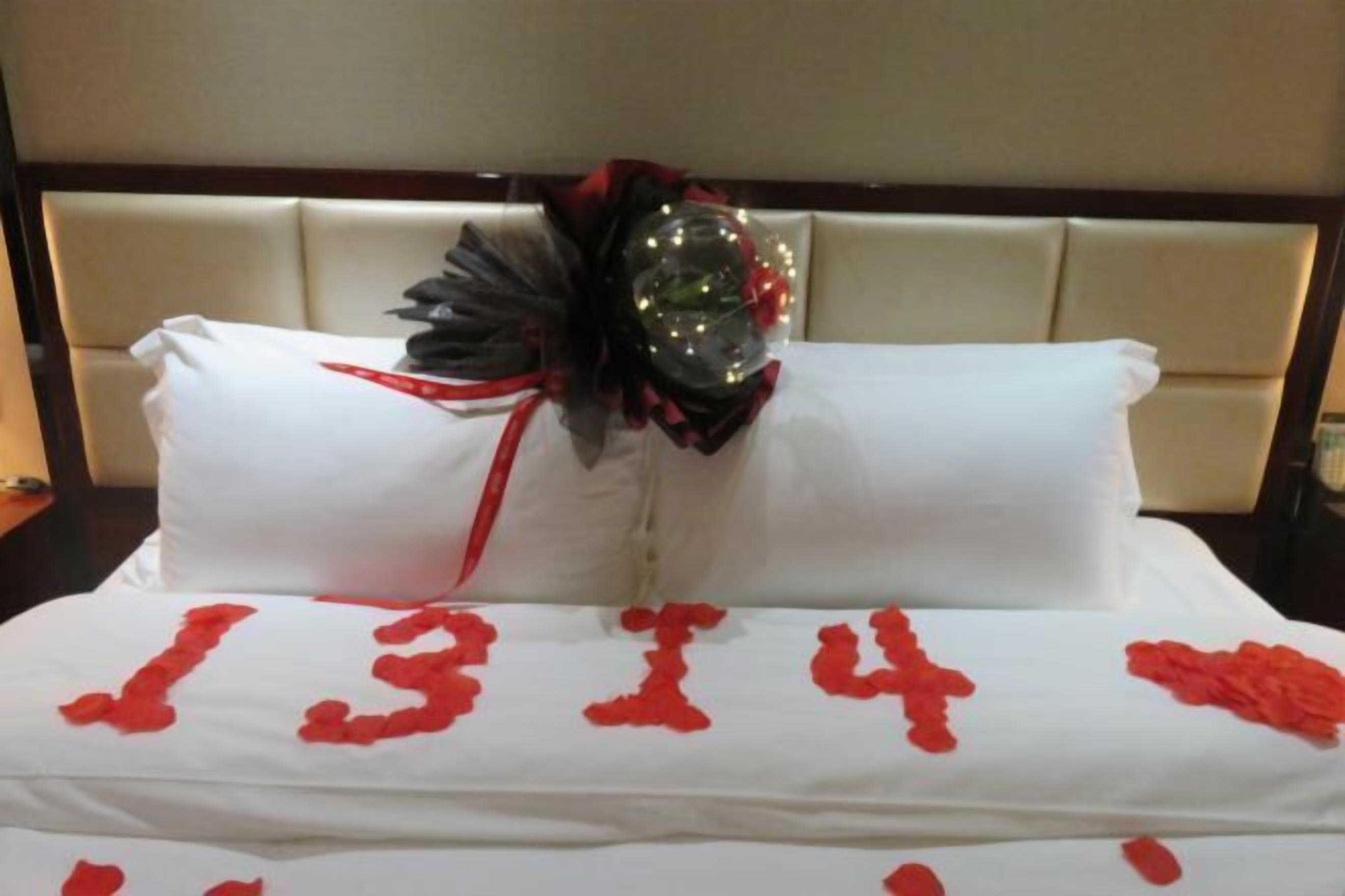 A bed with a white bedspread and red floral patterns.
