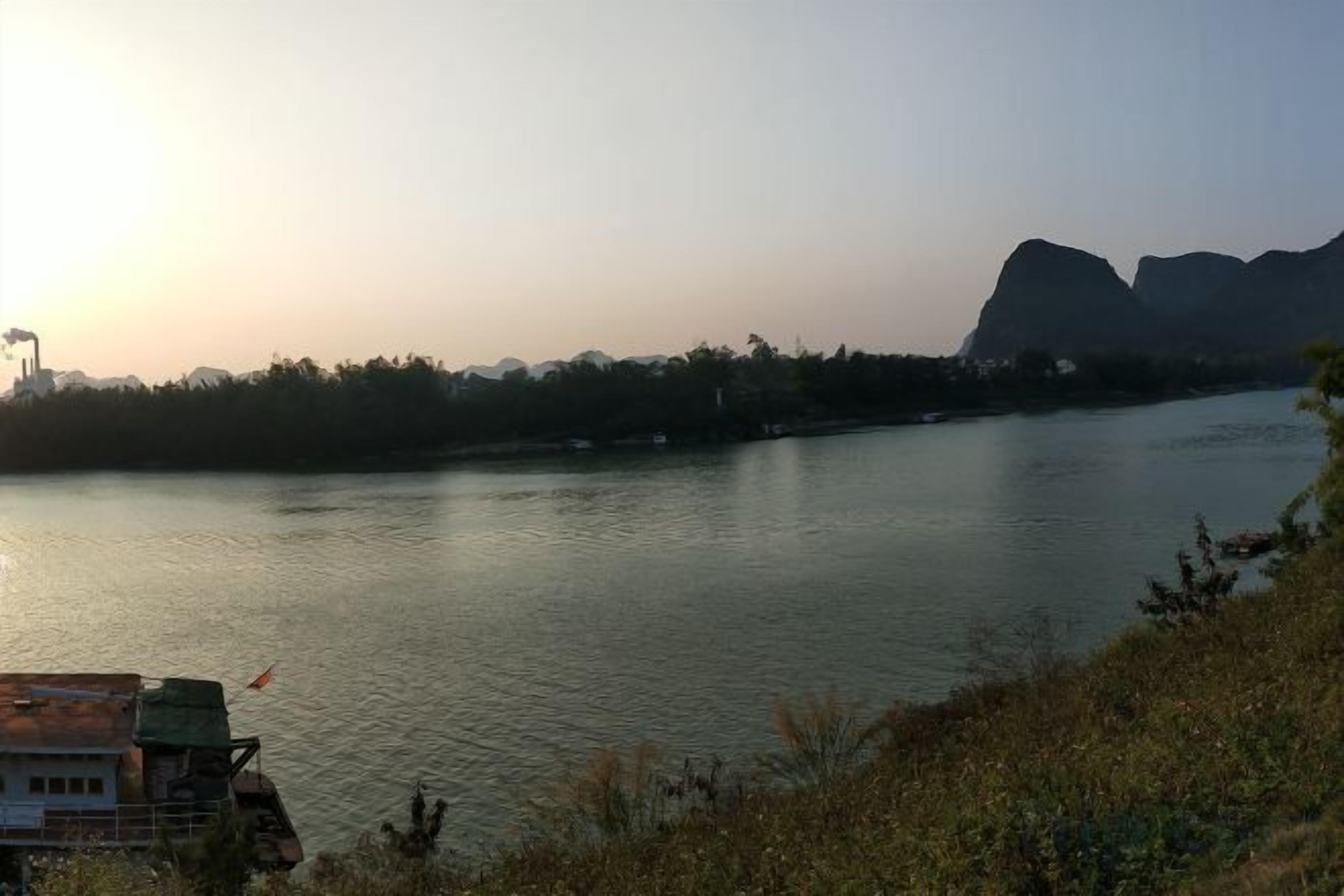 A river with a building on the left and mountains in the background.