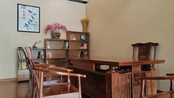 A traditional wooden desk with chairs, a bookshelf, and a framed picture on the wall.