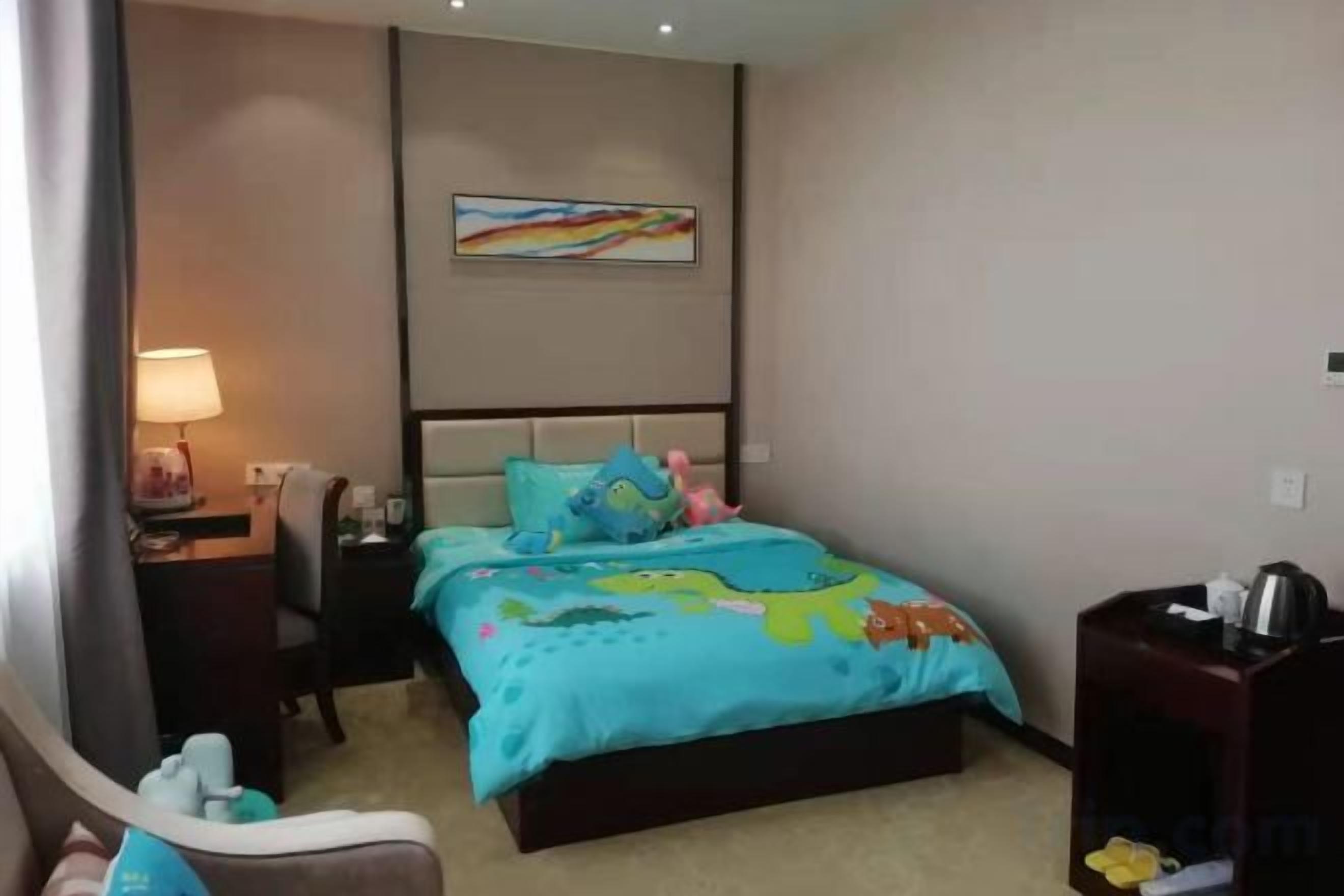 Una camera d'albergo con un letto, un comodino, una lampada, una sedia e un quadro appeso al muro.