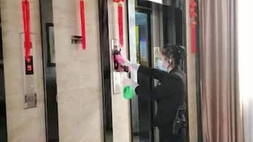 Una persona de pie en un ascensor con dispensador de gel antibacterial.