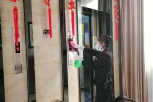 Una persona de pie en un ascensor con dispensador de gel antibacterial.