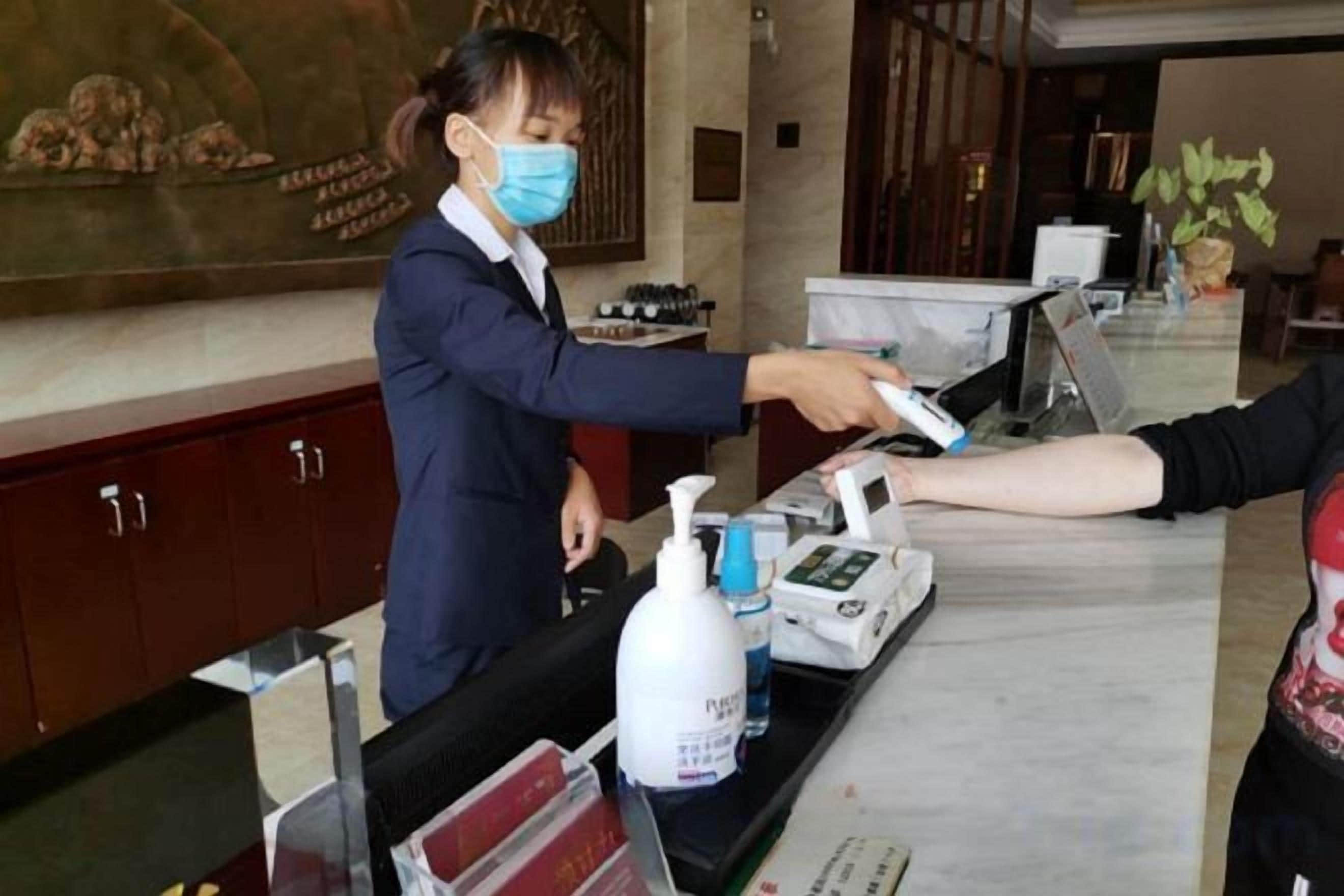 A reception area with a counter, a digital device, and a bottle of hand sanitizer.