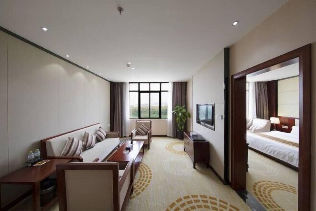 A hotel room with a bed, a desk, a chair, a TV, and a large window.