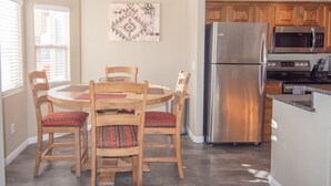 Una cocina moderna con refrigerador de acero inoxidable, armarios de madera y un comedor con mesa y sillas redondas.