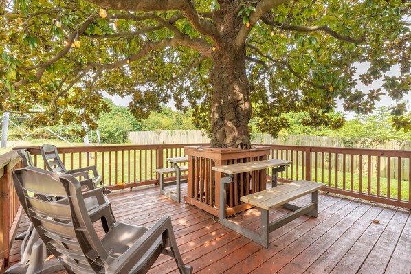 Relax on the shaded deck surrounded by lush greenery and enjoy a meal at the wooden picnic table.