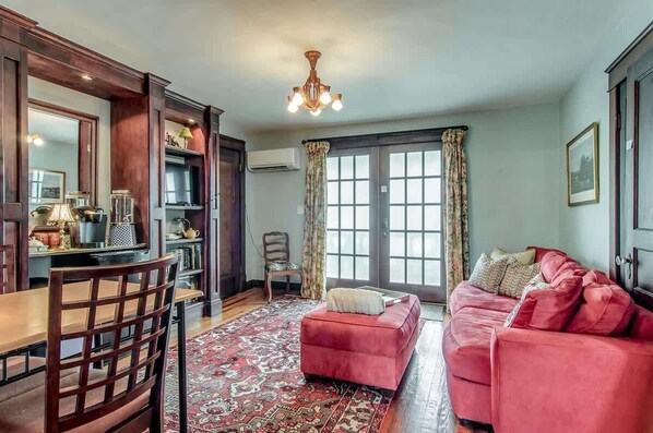 A living room with a red sofa, a wooden dining table, and a patterned rug.