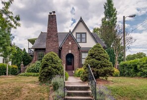 A two-story house with a brick facade, a prominent chimney, and a front entrance with steps.