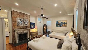 A hotel room with two beds, a fireplace, and artwork on the walls. - Market Street House - Enchanted Victorian (Nashville)
