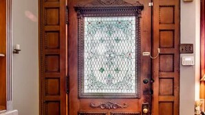 A wooden door with a decorative glass panel and a small window above it. - Market Street House - Enchanted Victorian (Nashville)