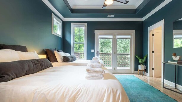 Un dormitorio con una cama grande, un ventilador de techo y vistas al exterior a través de una puerta corrediza de vidrio.